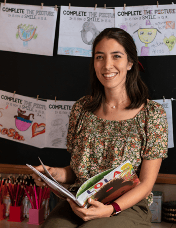Angie Ringhauser M.Ed., Literacy Studies, Dual Language 2nd Grade Teacher holding a book