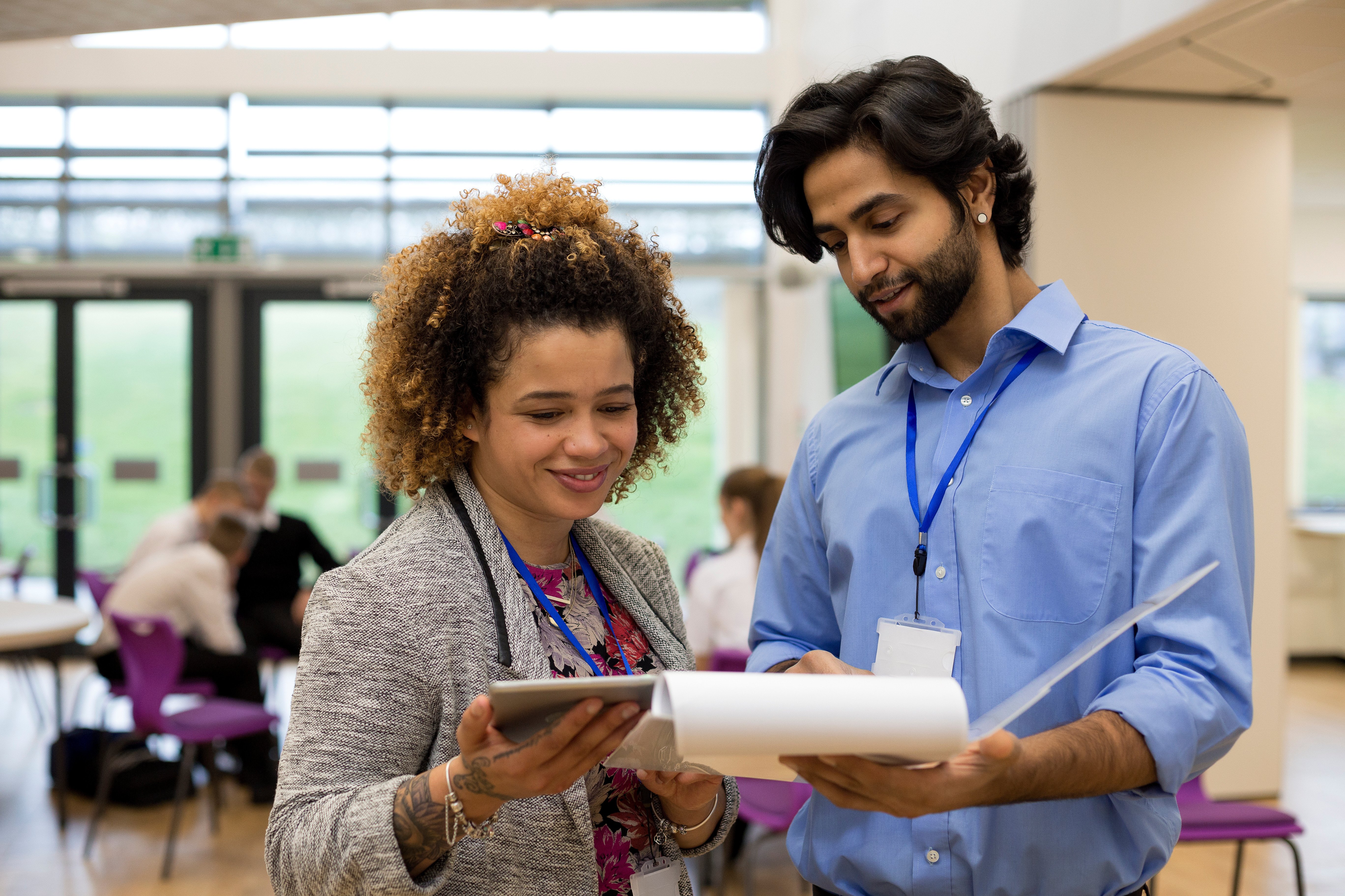 two graduate students looking over notes in a classroom setting