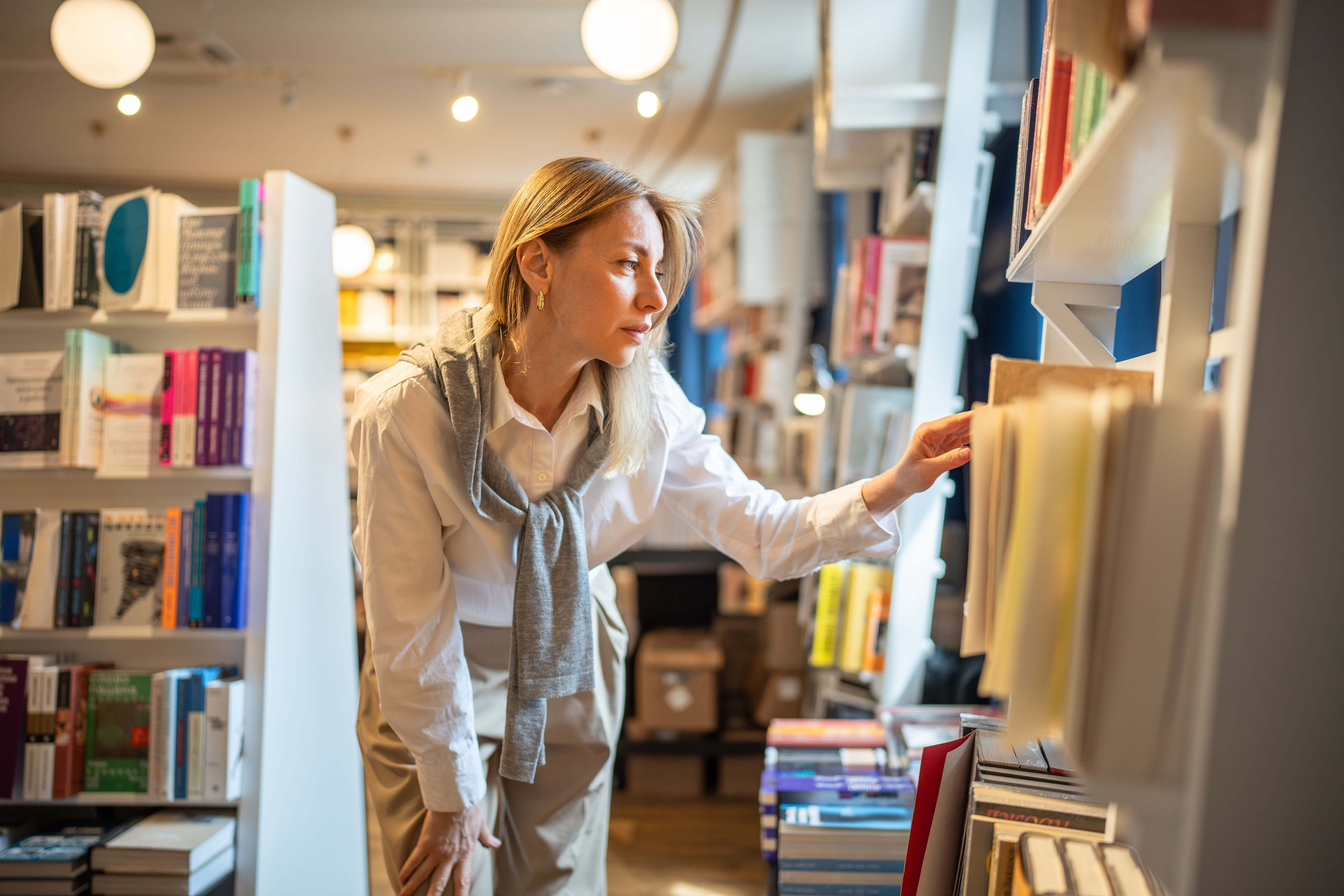 Enthusiastic woman selects books in bookstore alone
