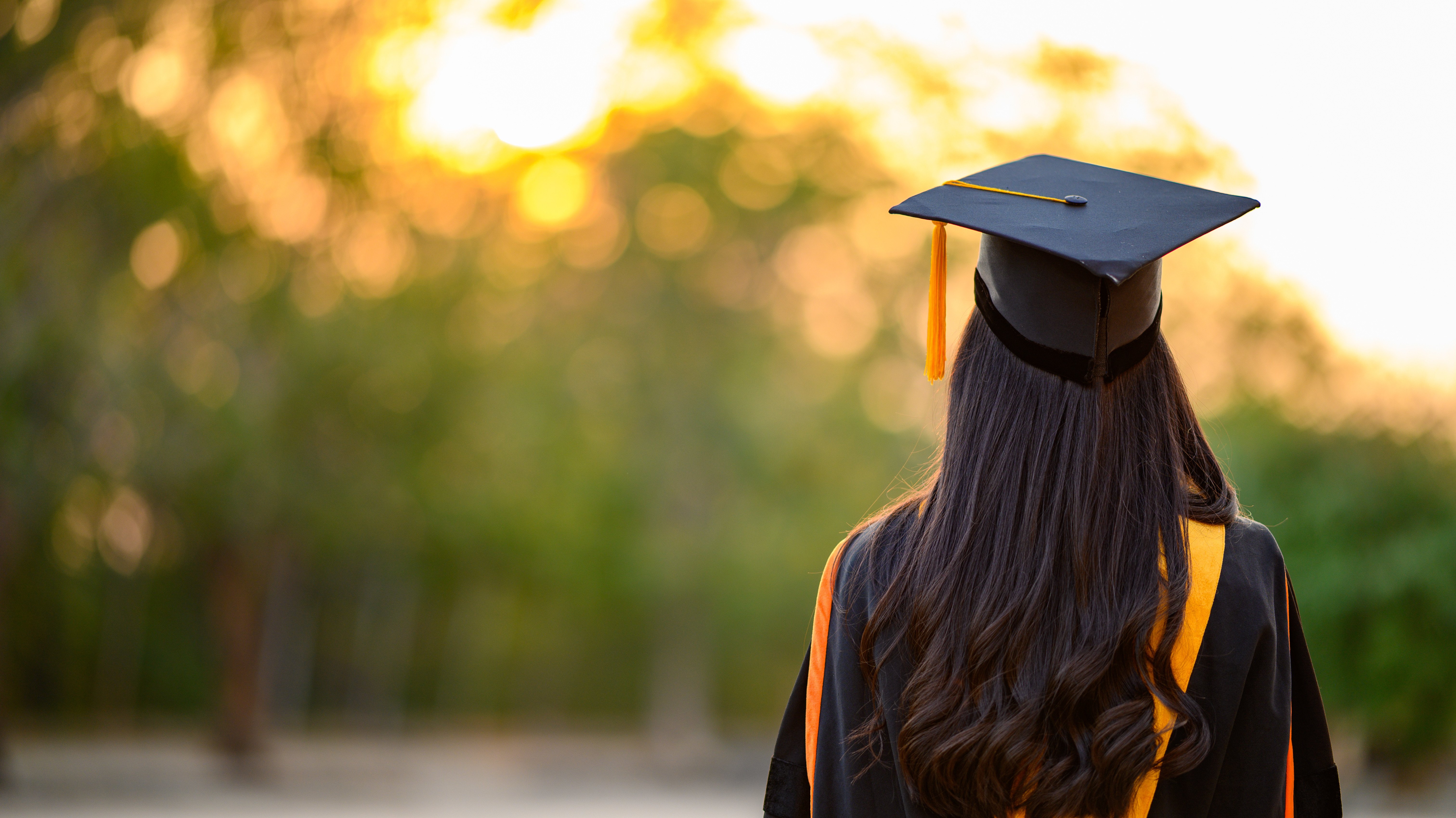 Female graduates wear black gowns and yellow tassels waiting to attend the commencement ceremony at the university.