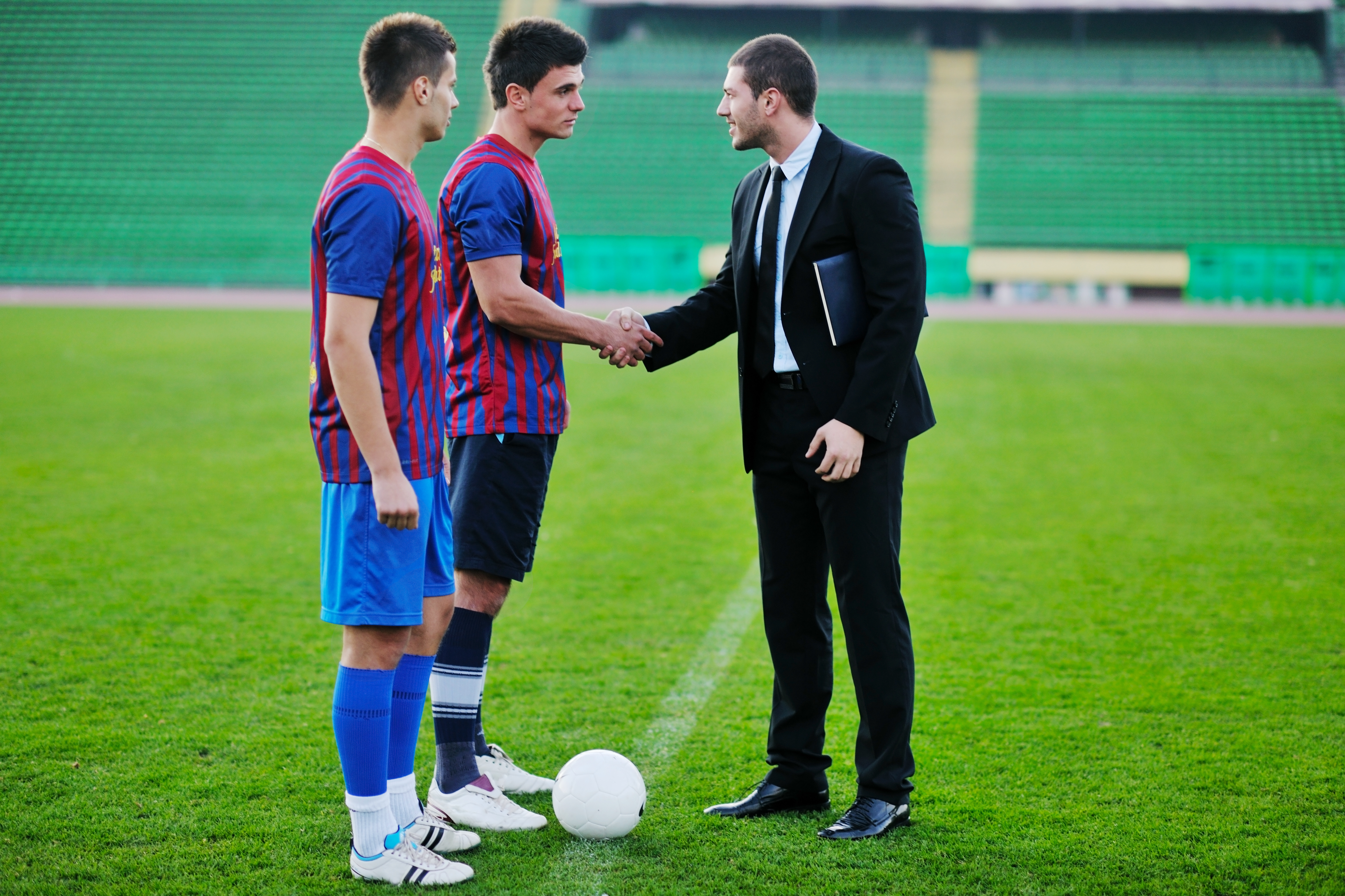 Two men shaking hands on a soccer field