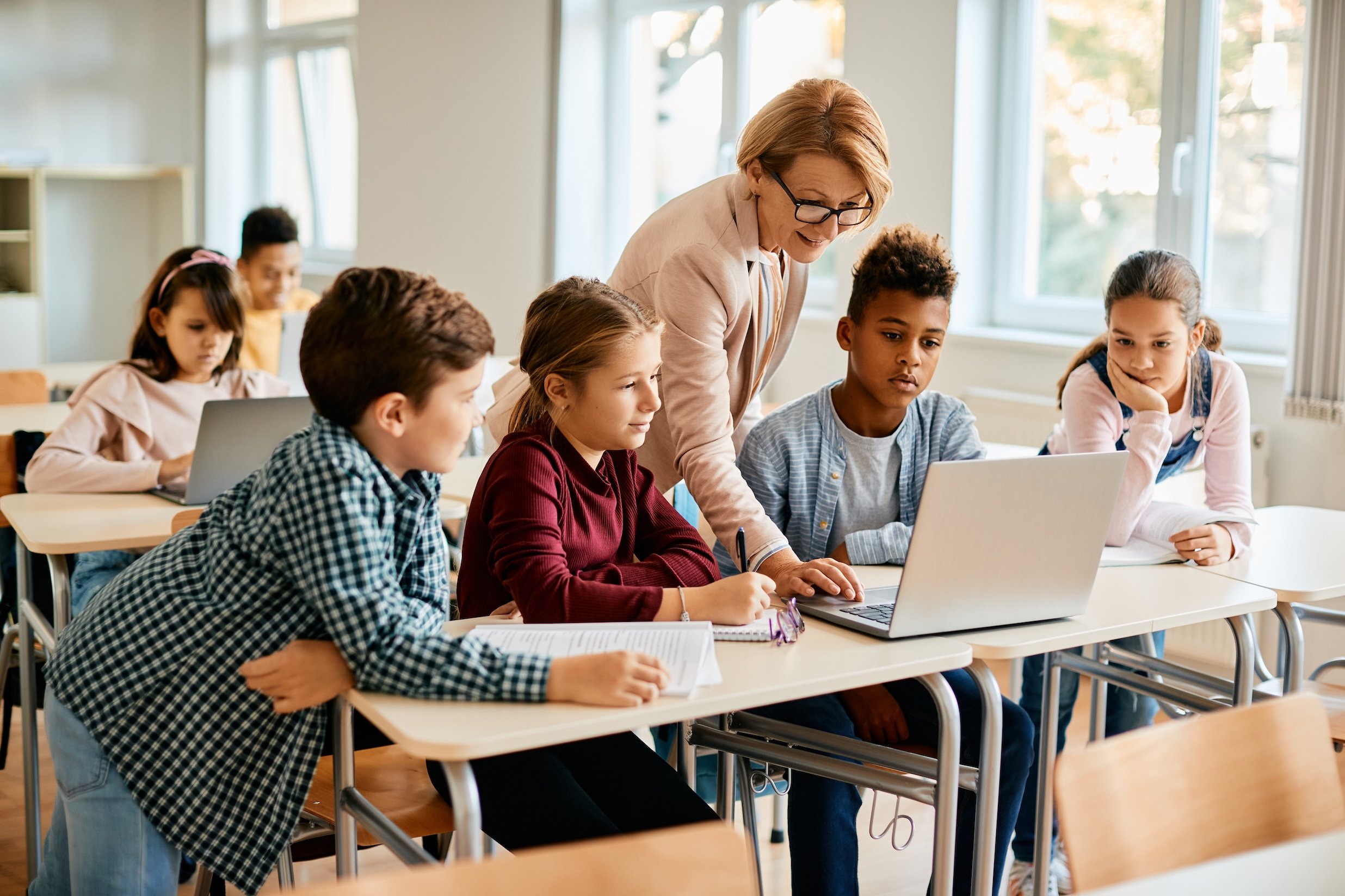 Group of elementary students having computer class with their teacher in classroom.