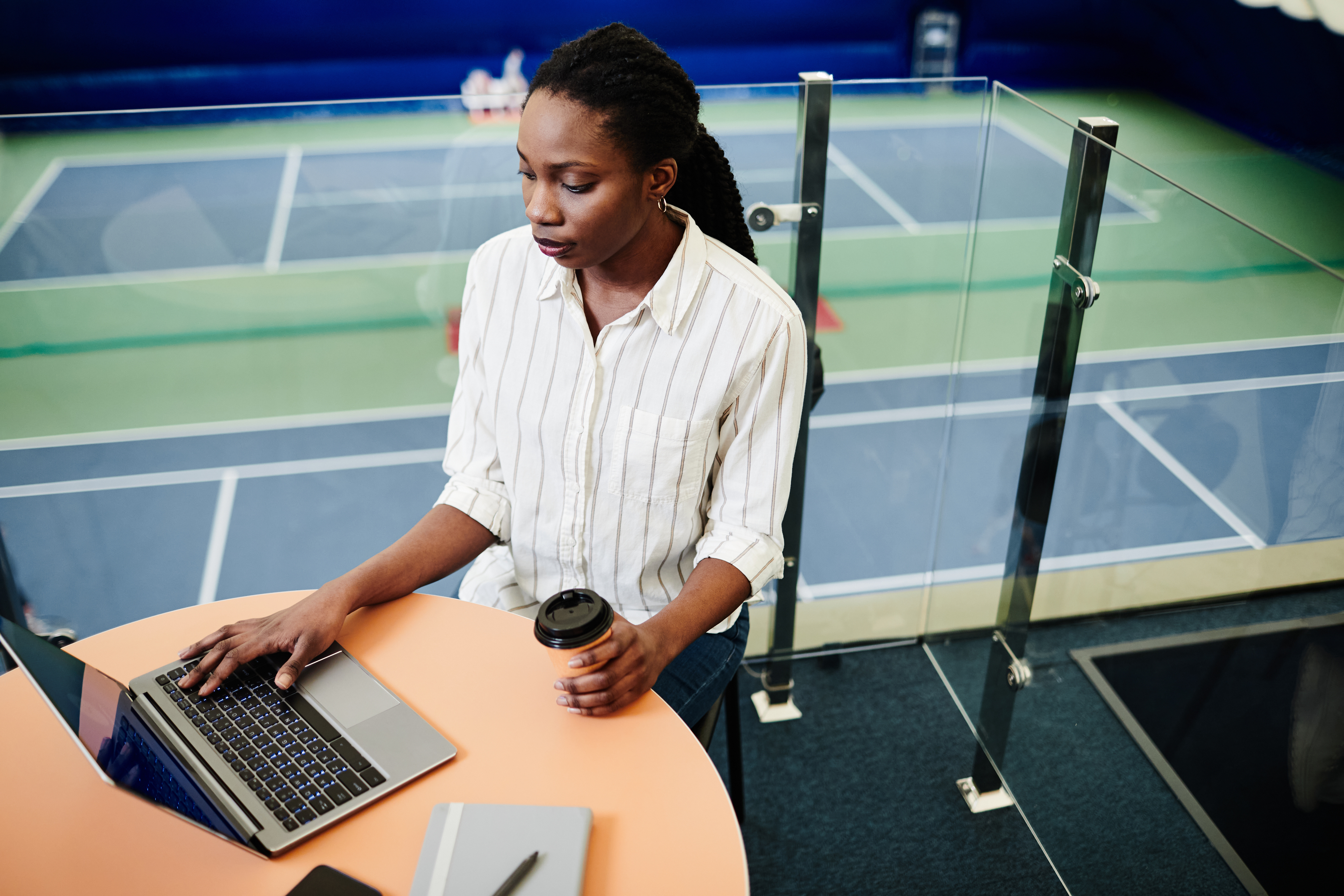 High angle portrait of young woman using laptop in sports training center