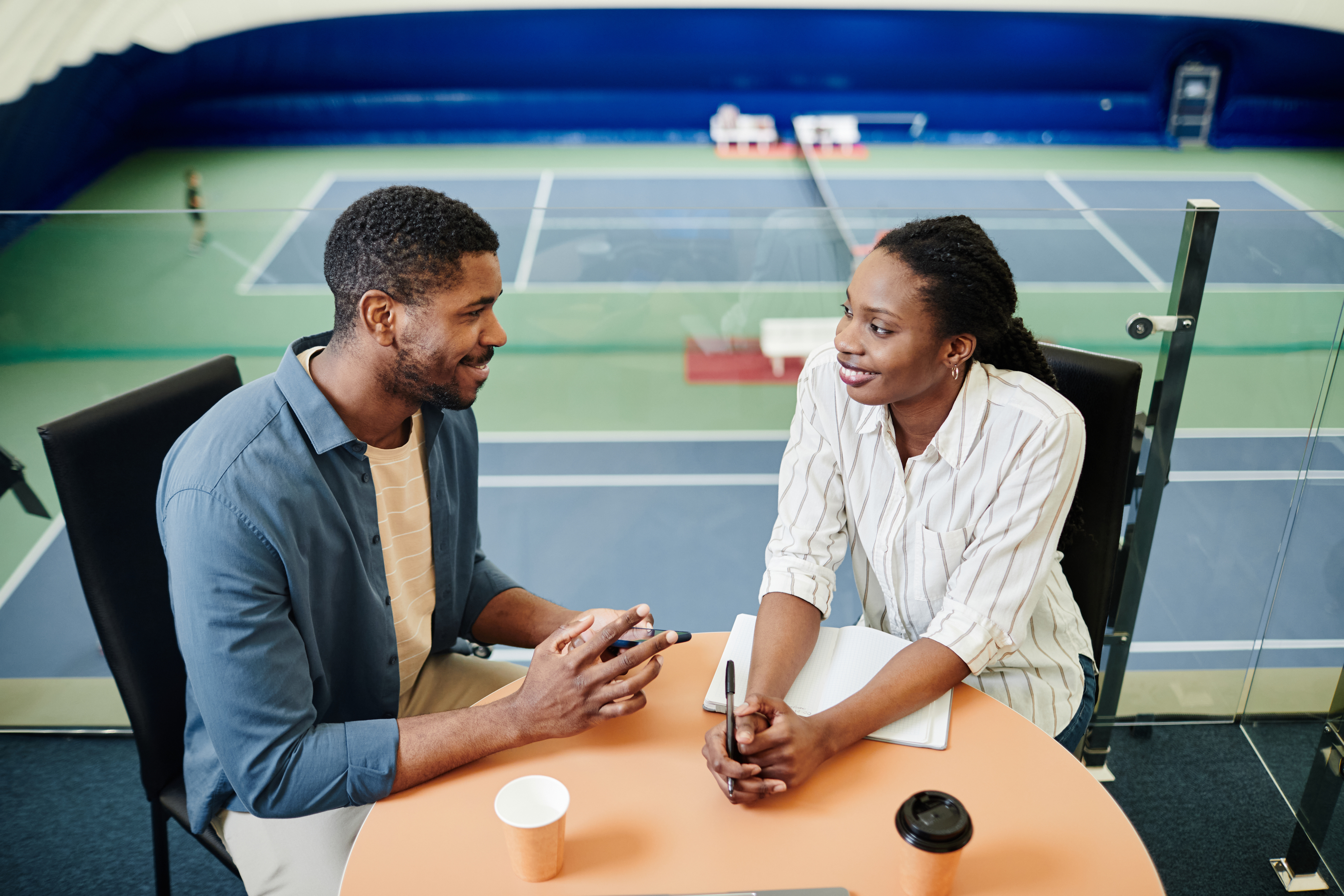 portrait of smiling black sportsman talking to female coach during after practice meeting 