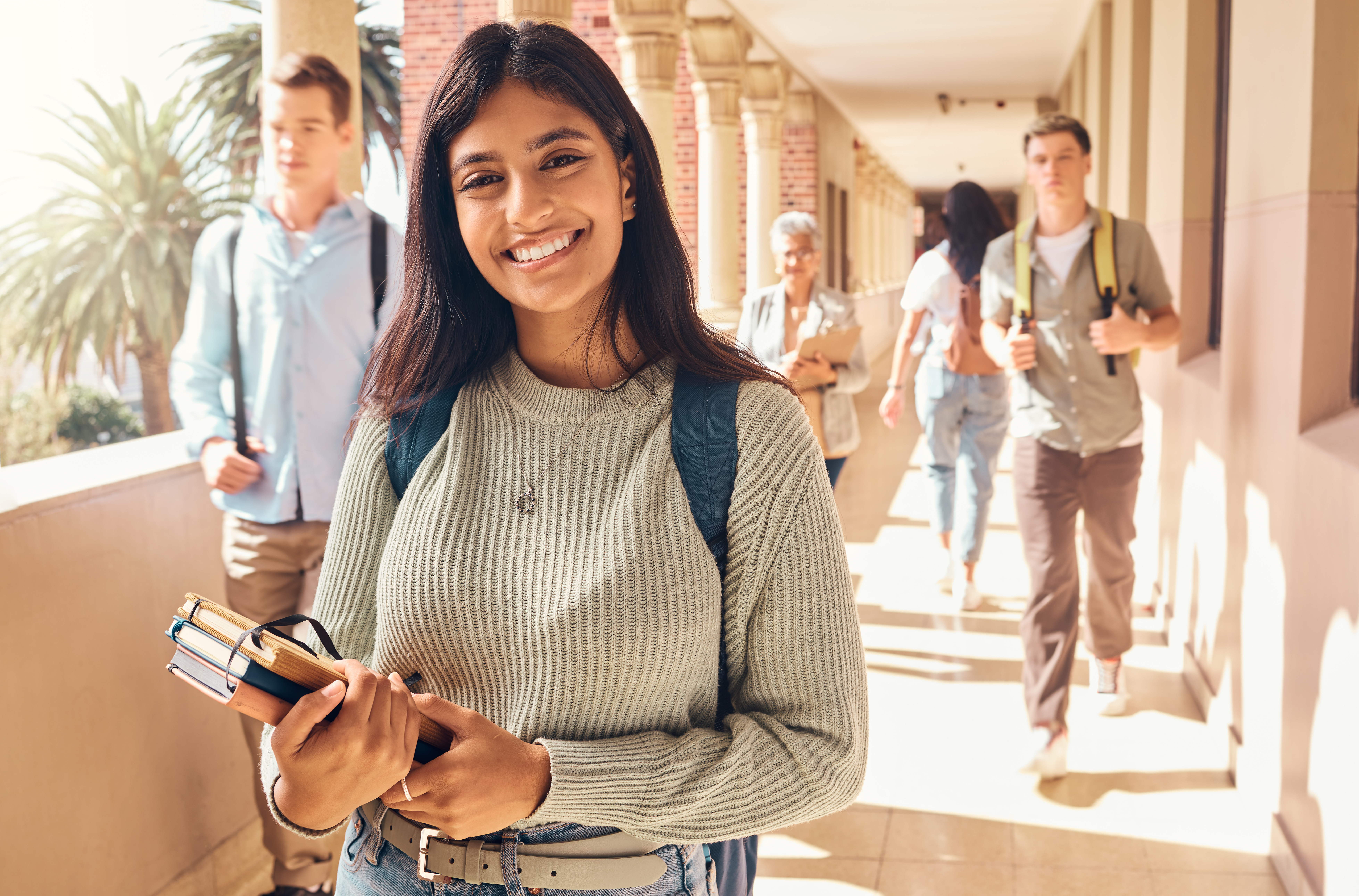 University student, indian woman and portrait at campus outdoor with books of learning, education or knowledge, scholarship and motivation. Happy, smile and young college student, studying or academy.