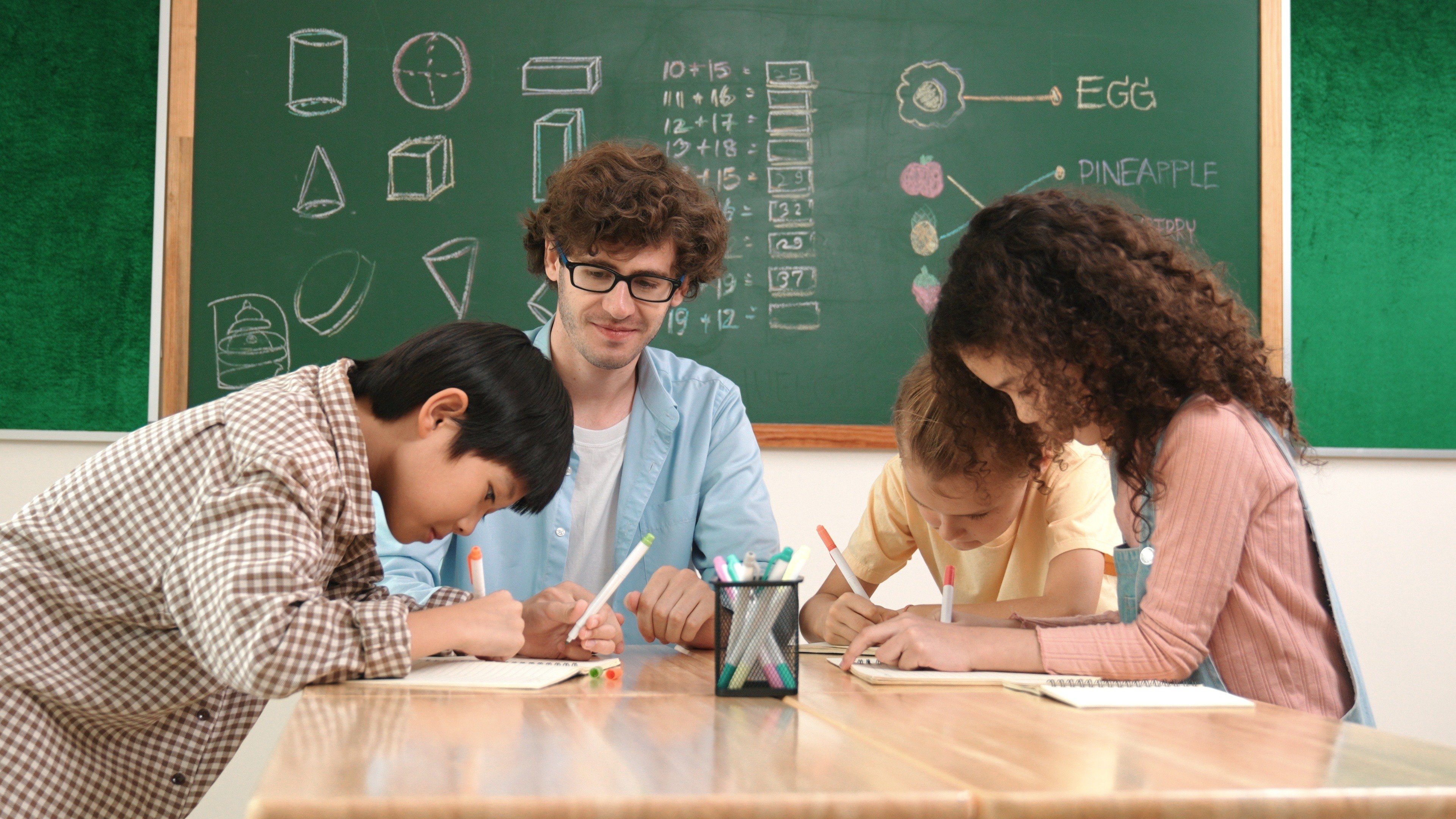 male teacher working with diverse children in a classroom